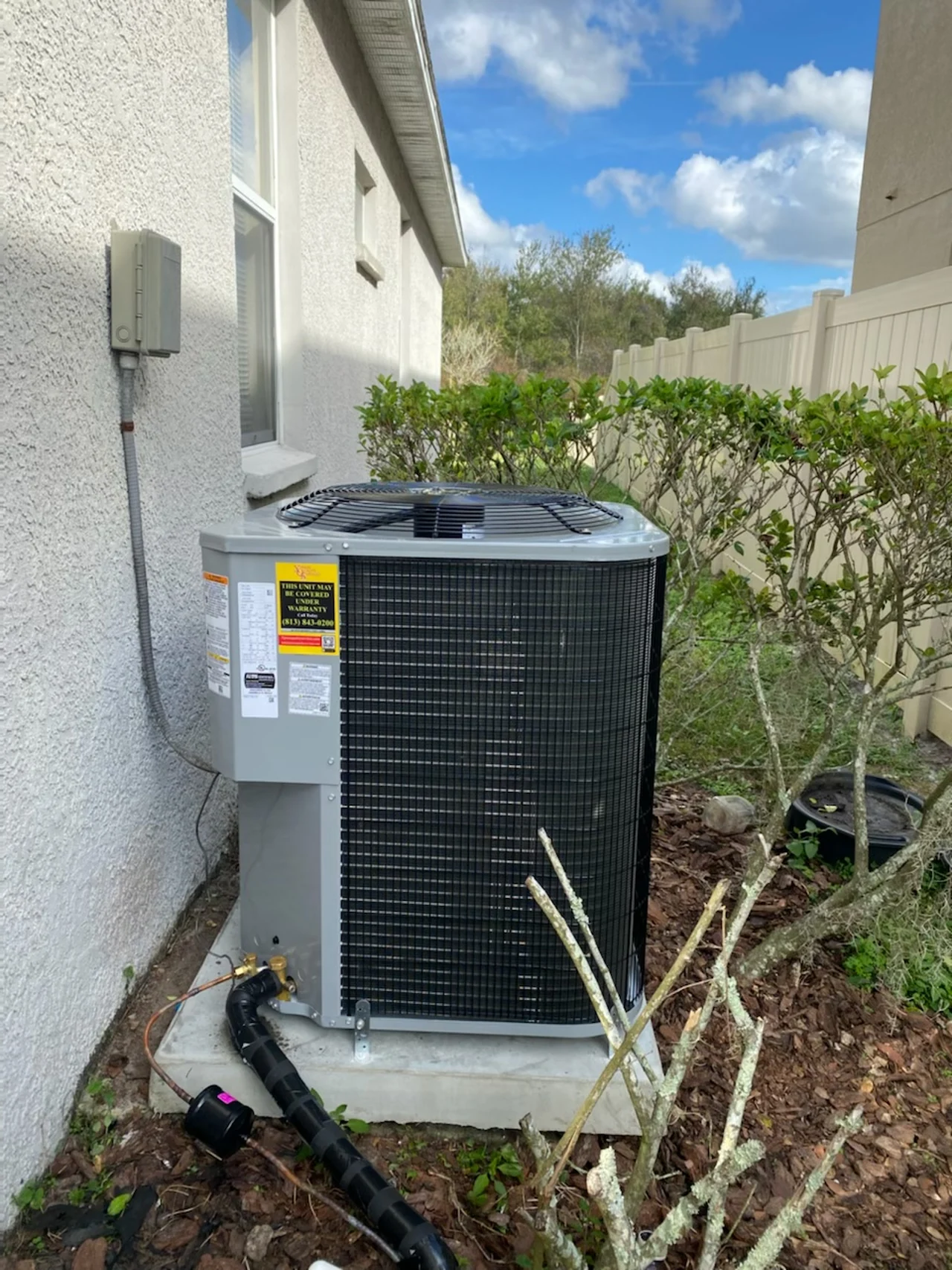 Outdoor air conditioner on a concrete pad beside a home
