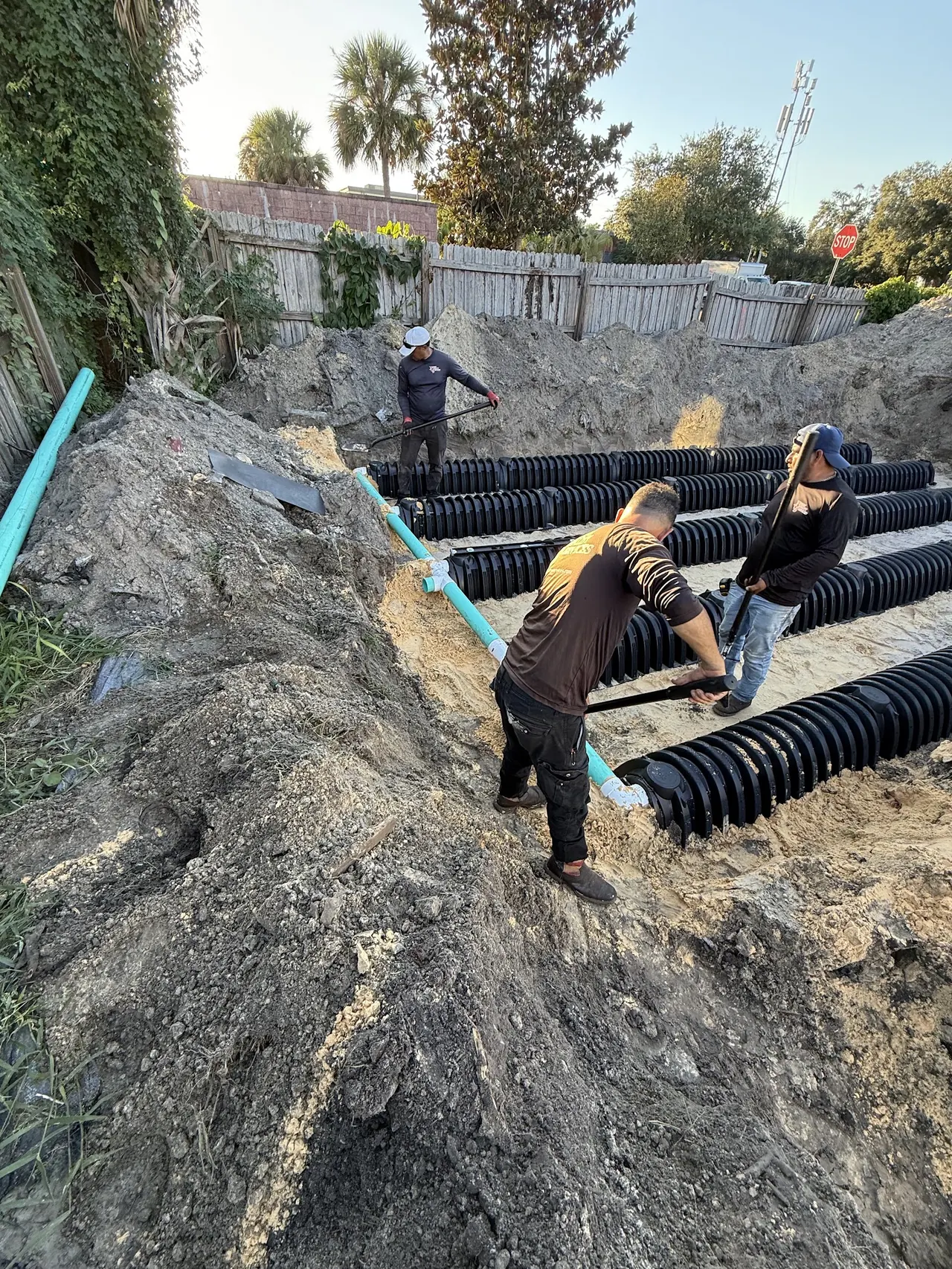 XQS crew laying drain field pipe in an excavated trench.