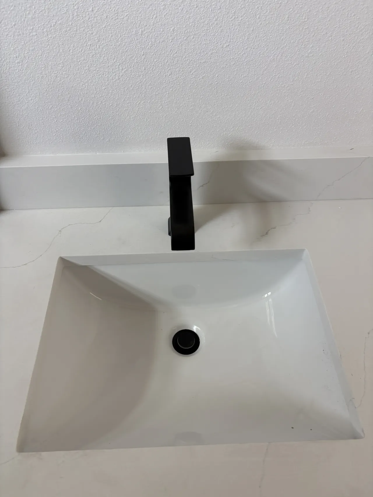 Bathroom sink and black faucet documented during an XQS plumbing job in Lutz.