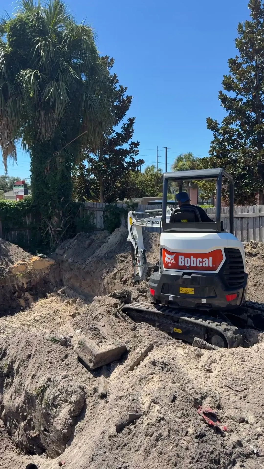 Mini excavator digging a septic system excavation at a residential lot