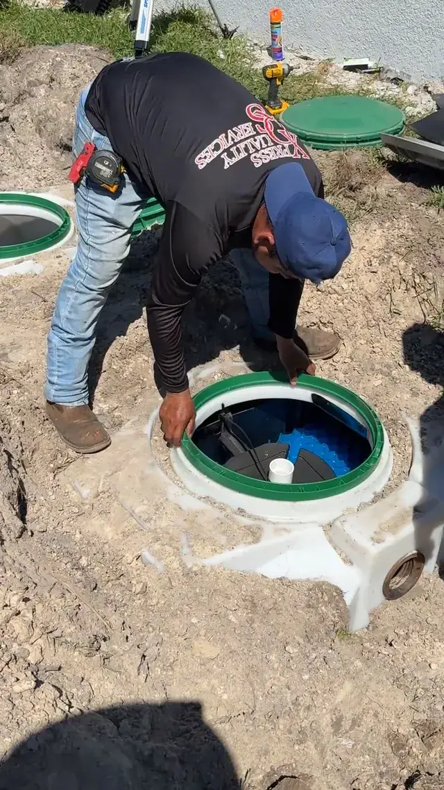 XQS technician working at an open septic tank access with its riser ring, XQS job video